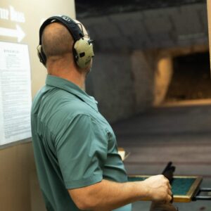 Man in a gun range looking at target far down the lane